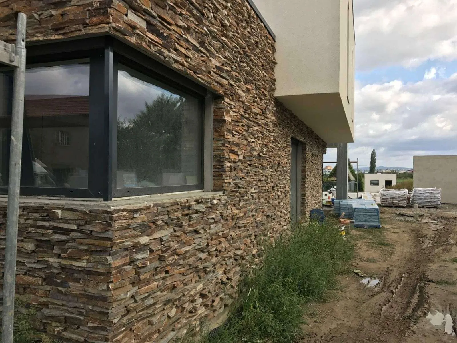 Modern house facade with dry-stacked irregular gneiss stone around a corner window