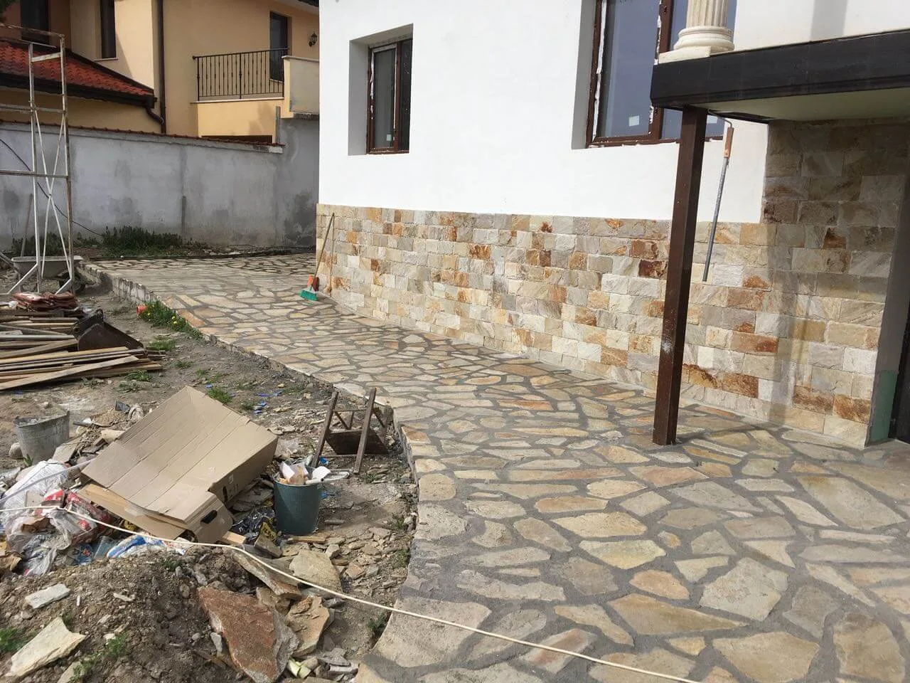 Irregular gneiss flagstone paving around a house with cut stone wall base