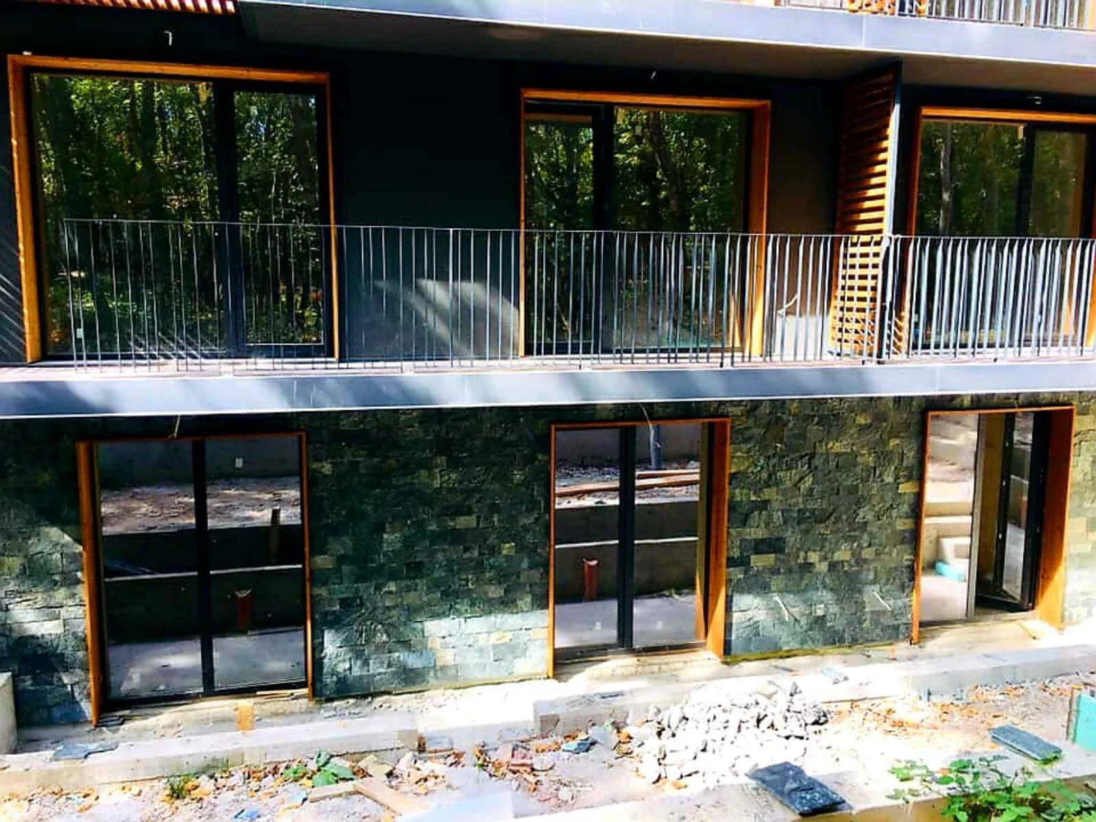 Ground-floor facade clad with green cut stone tiles beneath balconies