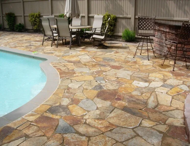 Irregular flagstone paving around a backyard swimming pool