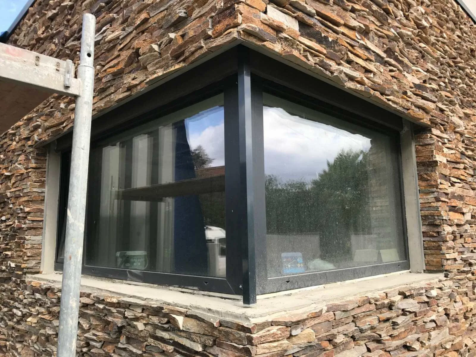 Corner window framed by dry-stacked irregular gneiss stone cladding