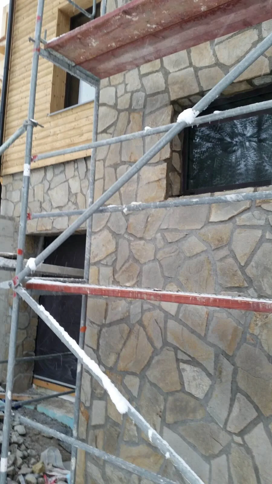 House facade clad with irregular gneiss flagstones seen through scaffolding