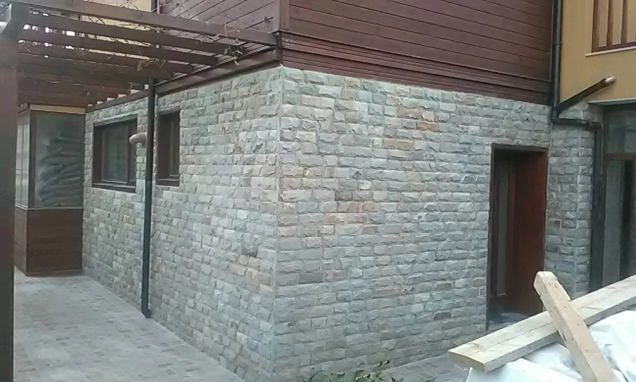 Exterior wall corner clad with regular cut grey gneiss blocks