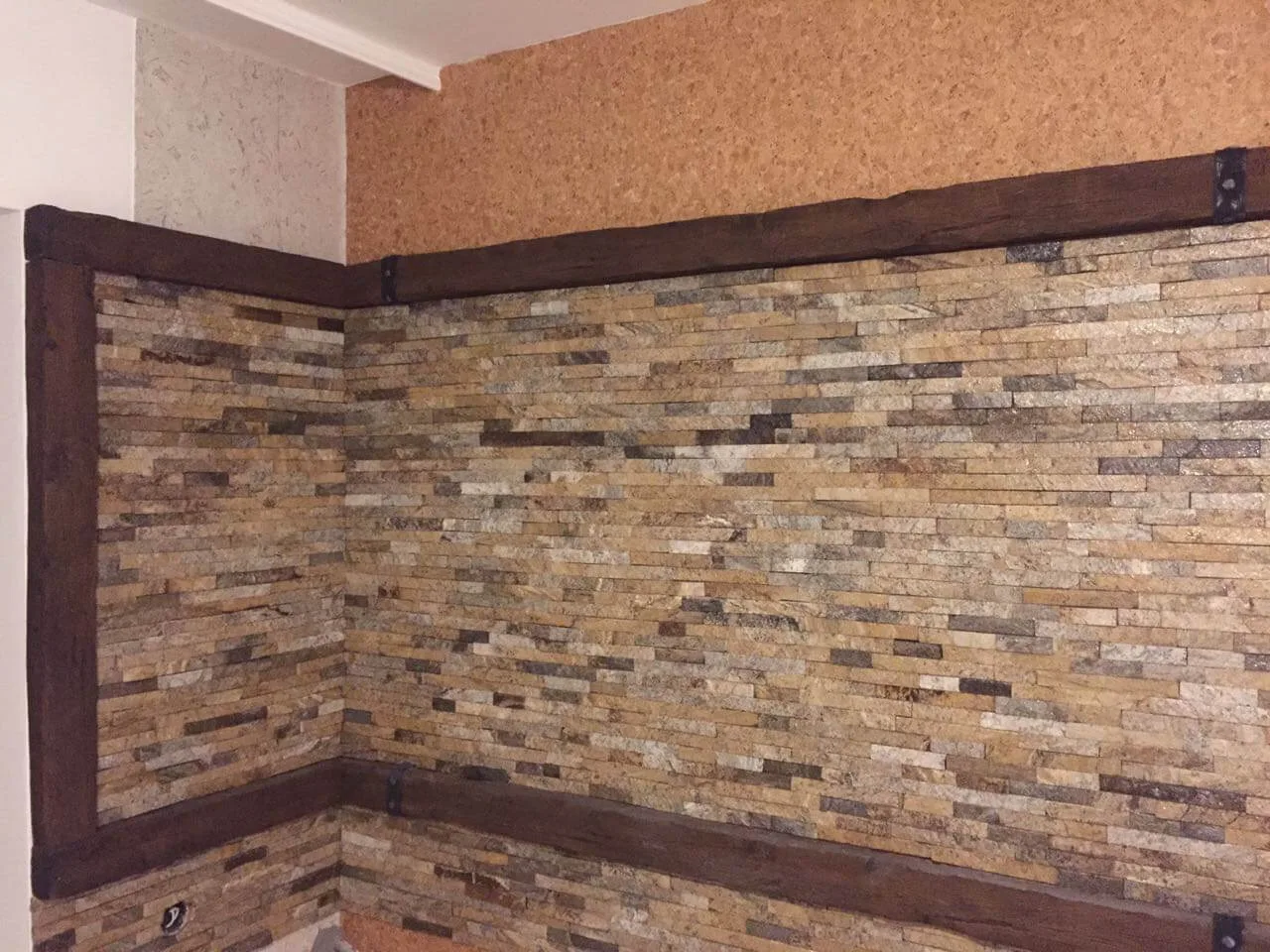 Interior feature wall with stacked stone strips framed by rustic wood beams