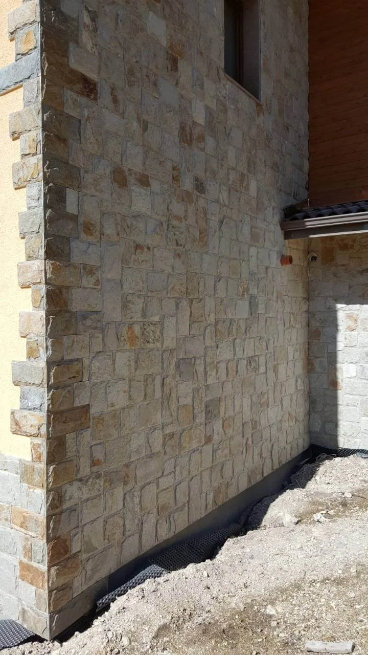 House facade corner clad with cut gneiss stone in varied sizes