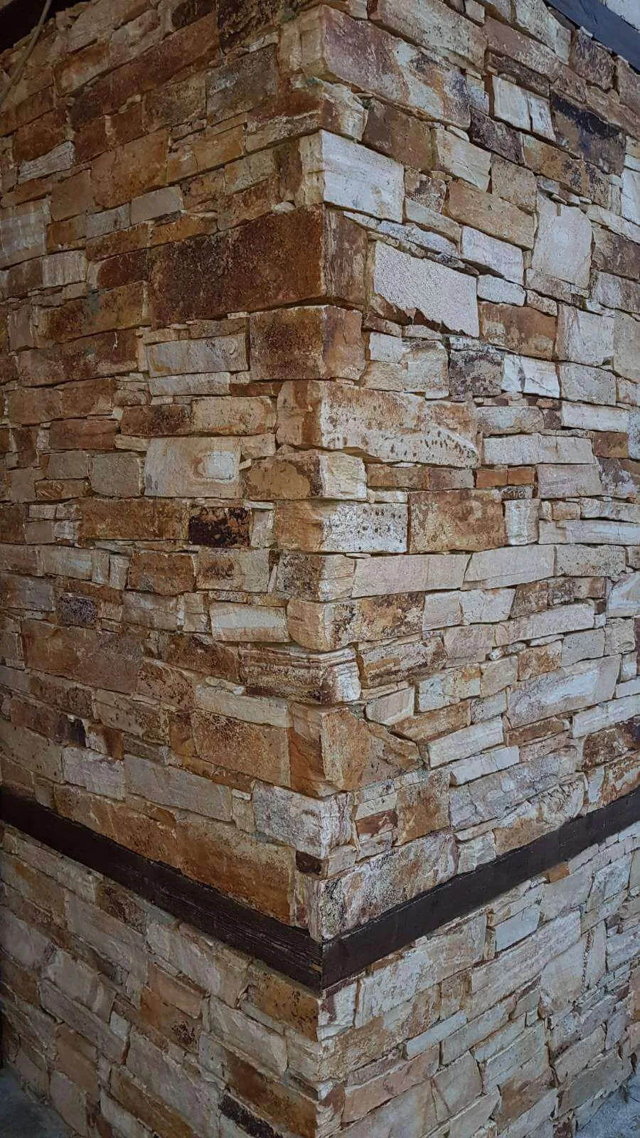 Corner detail of rustic stacked stone strip cladding in warm brown tones