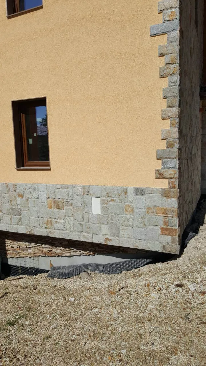 House corner with cut stone plinth cladding and stone quoins on the edge