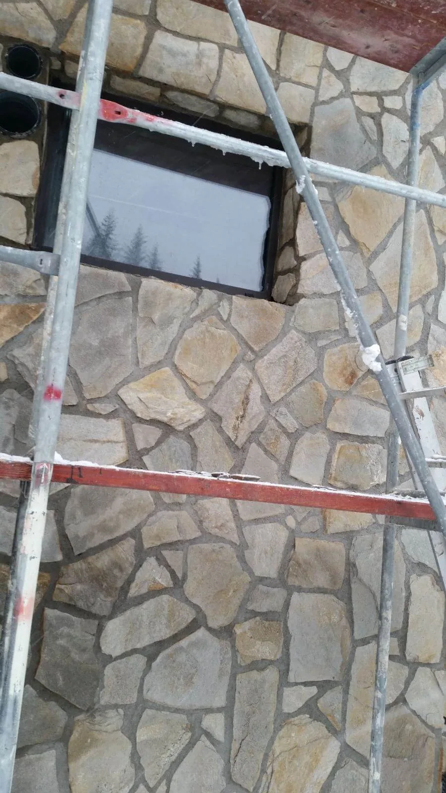 Polygonal gneiss flagstone cladding around a window during installation