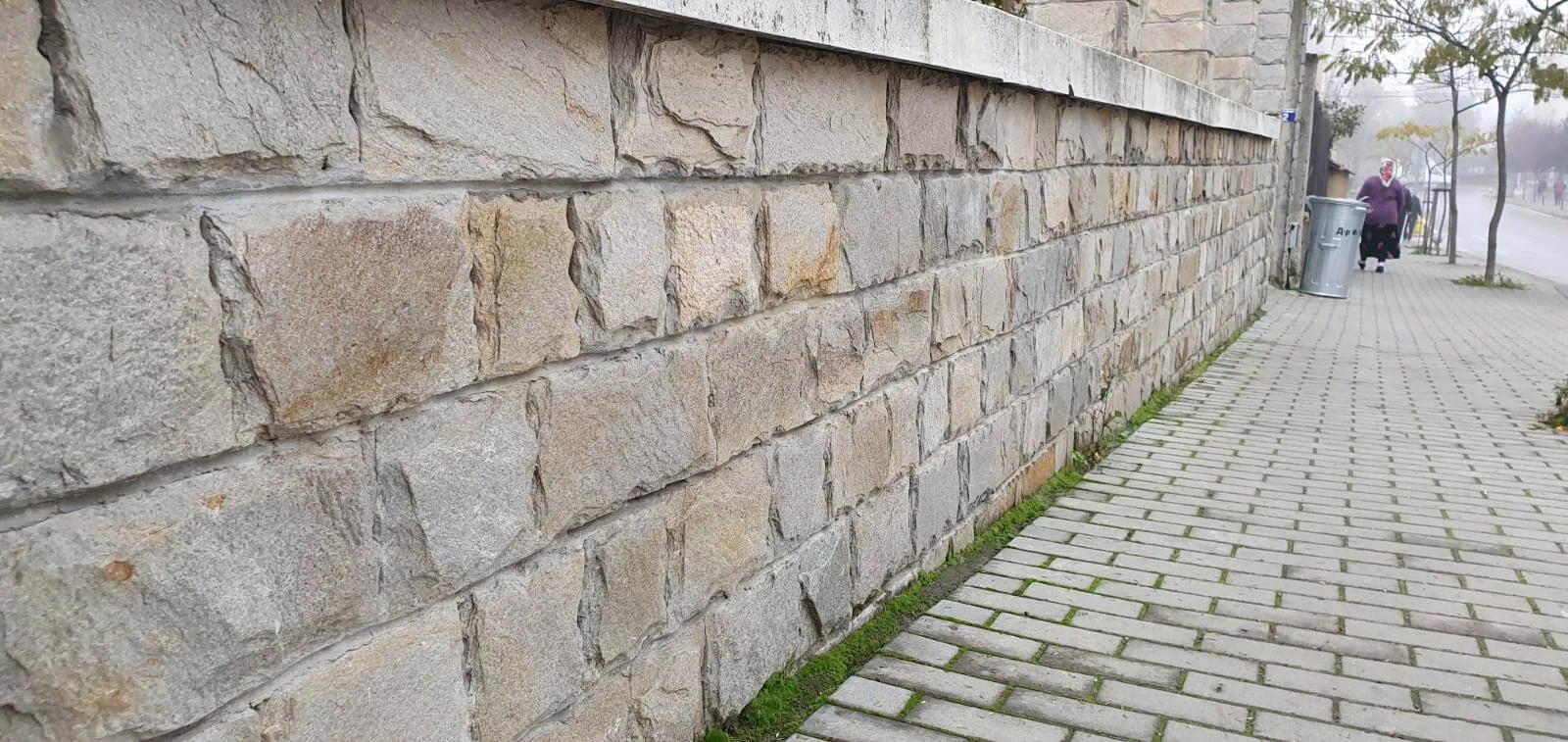 Street fence wall clad with rough-faced rectangular gneiss blocks