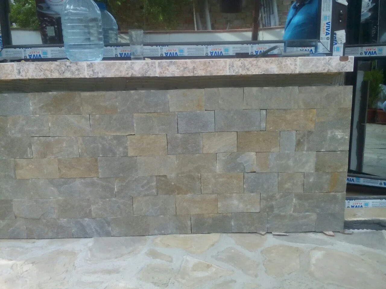 Outdoor counter clad with cut gneiss rectangles beneath a stone worktop