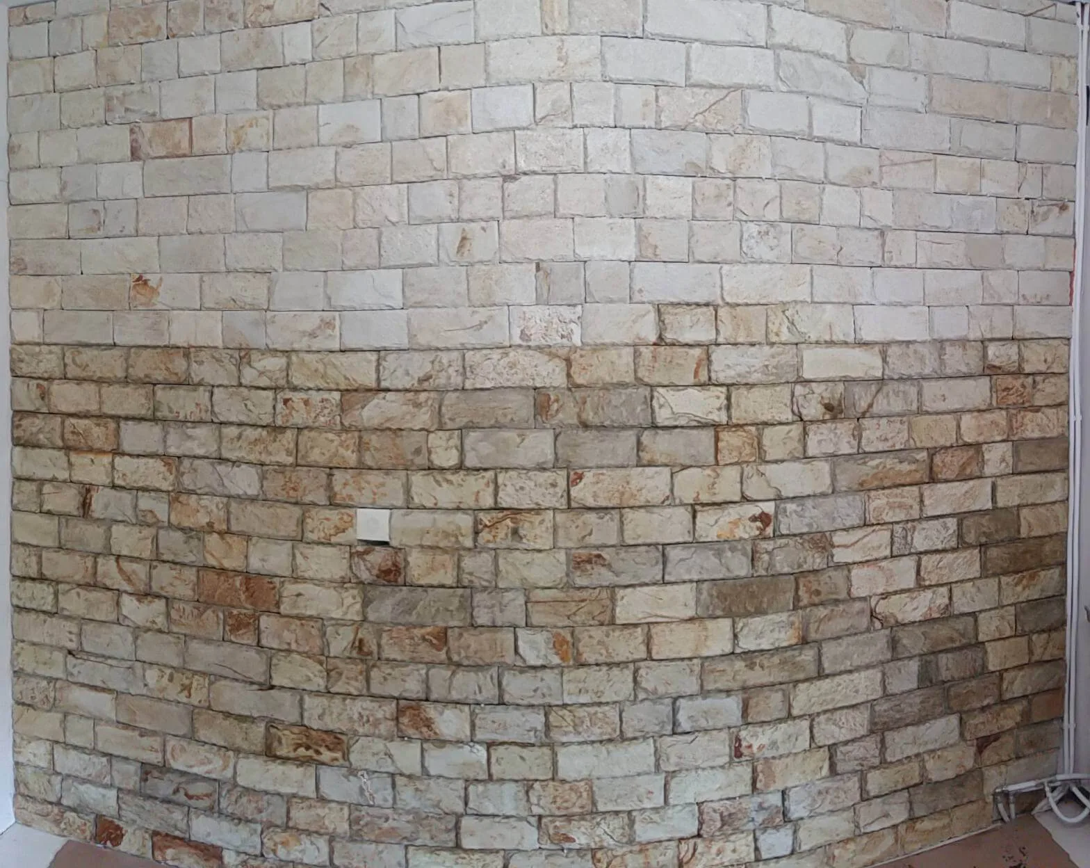 Curved interior wall clad with cream rectangular stone blocks