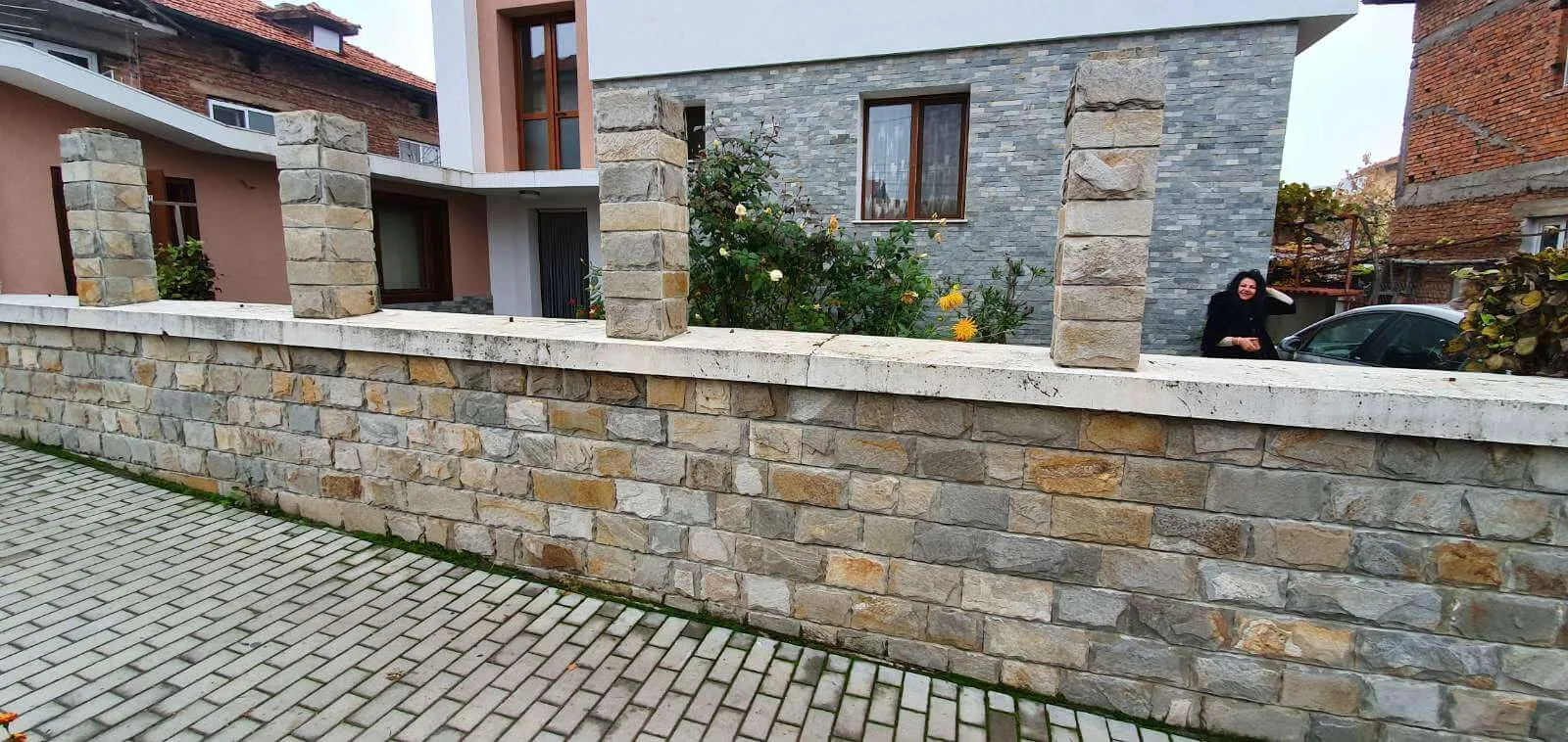 Garden fence wall built from irregular gneiss blocks with stone pillars