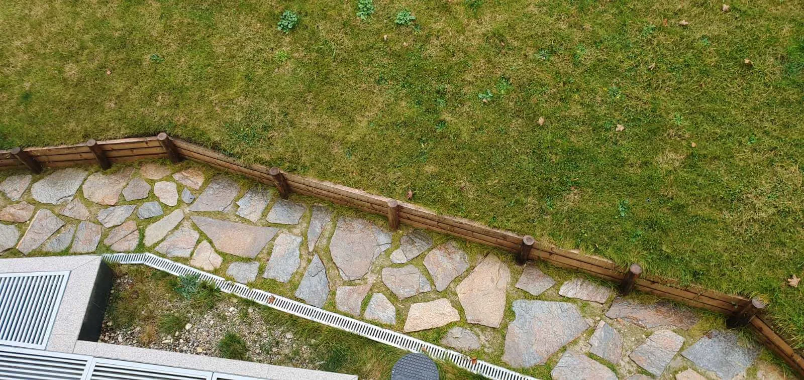 Irregular gneiss flagstone path beside a lawn with wooden edging