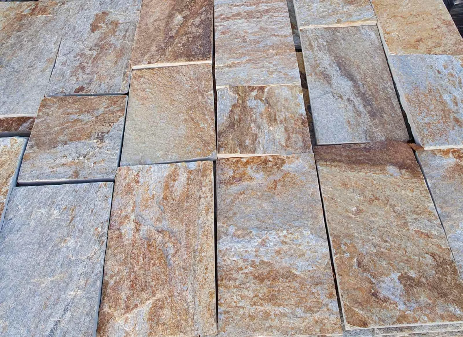 Close-up of precision-cut gneiss paving tiles in rust and grey tones