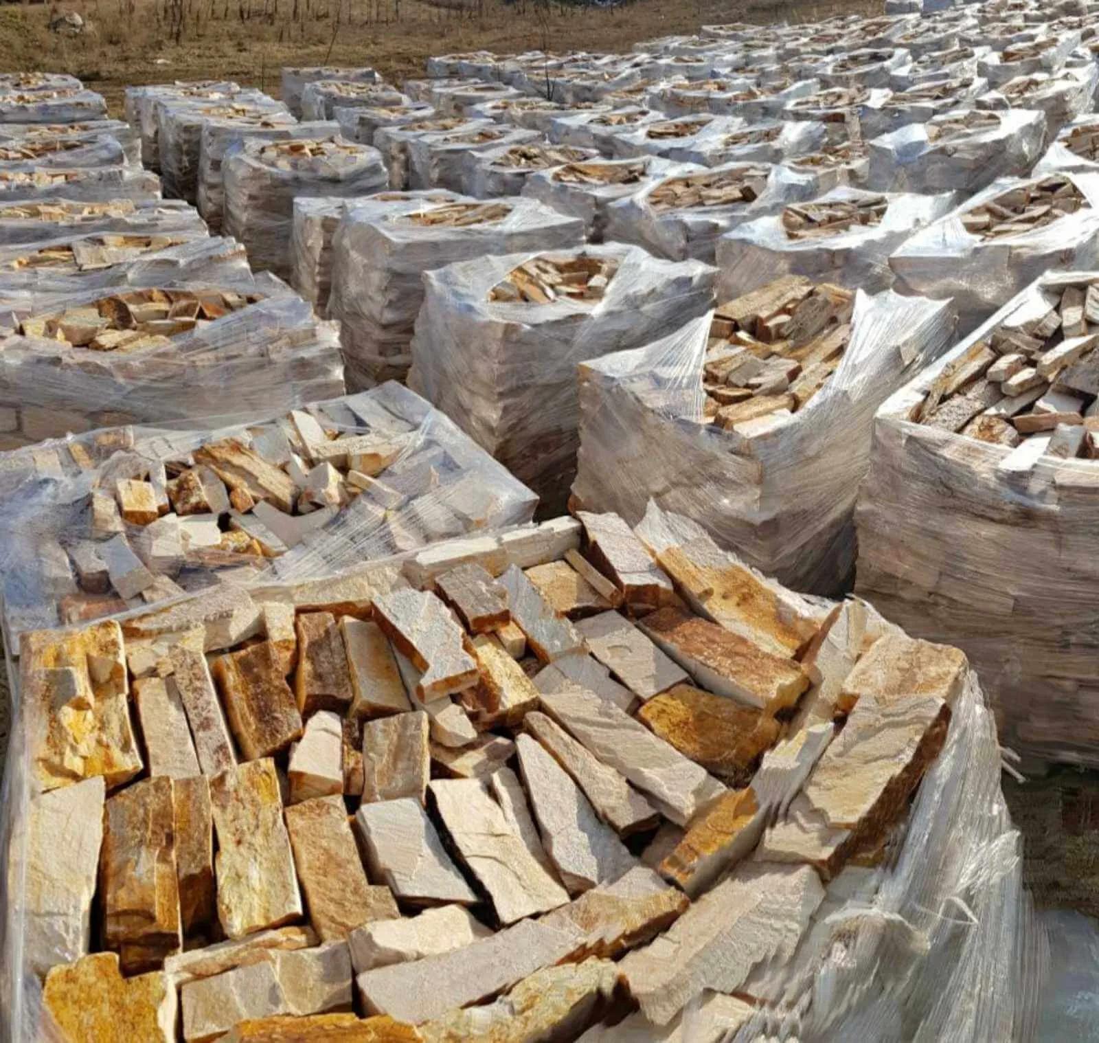 Rows of palletized rubble building stone at the production yard