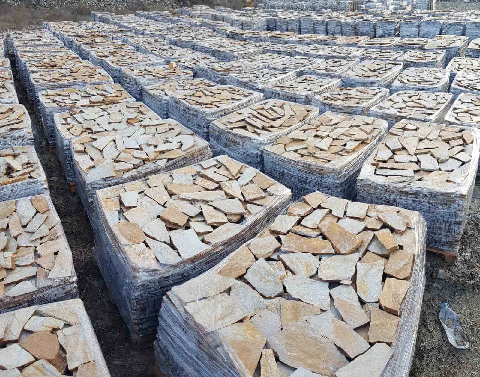Pallets of irregular gneiss flagstones stacked at the stone yard
