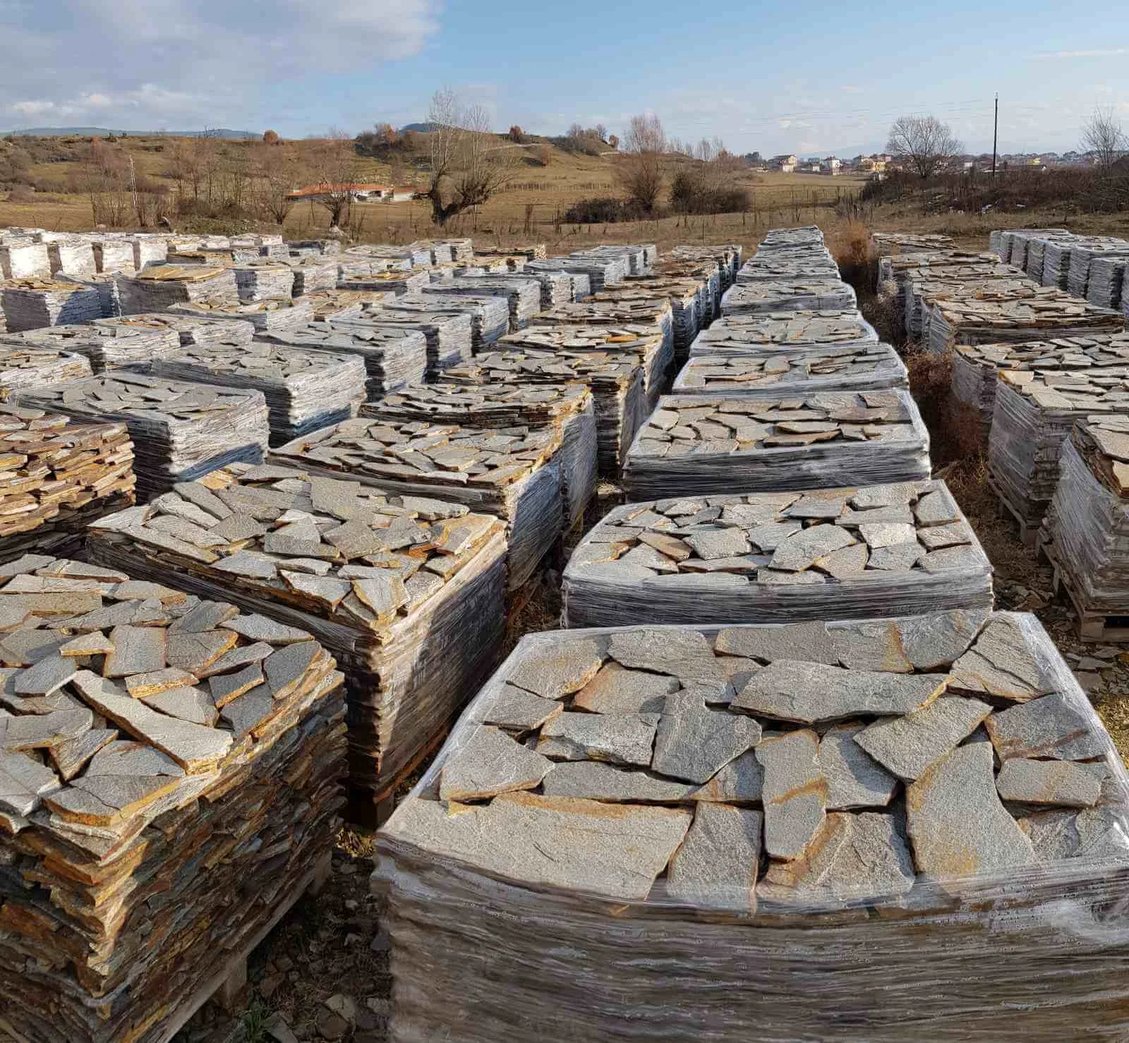 Stone yard with rows of palletized grey gneiss flagstones