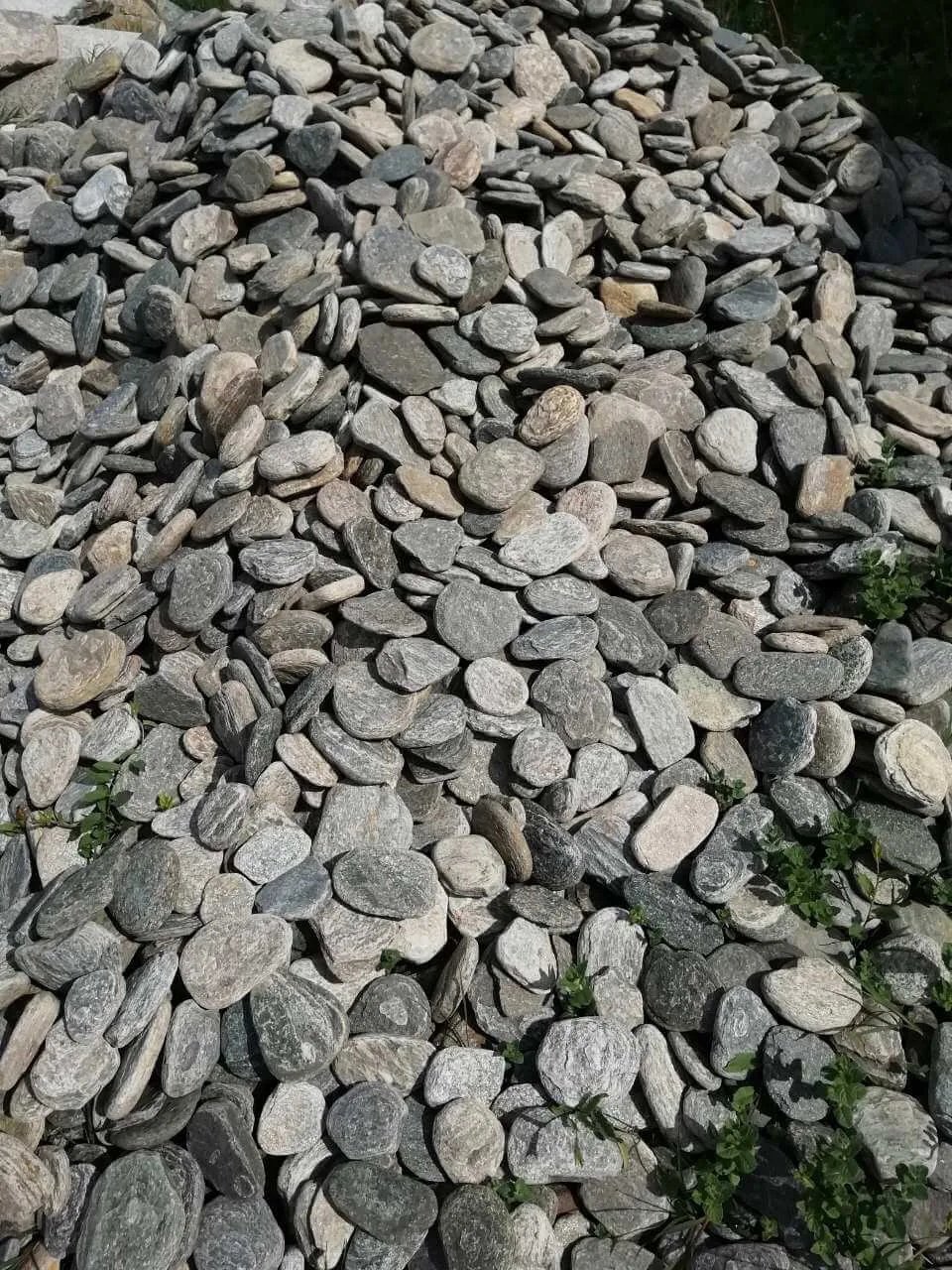 Pile of flat grey decorative pebbles for garden landscaping