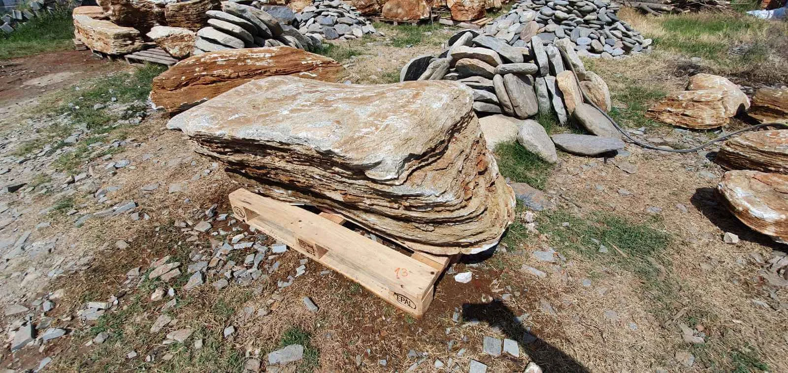 Large layered gneiss boulder for garden decoration resting on a wooden pallet.