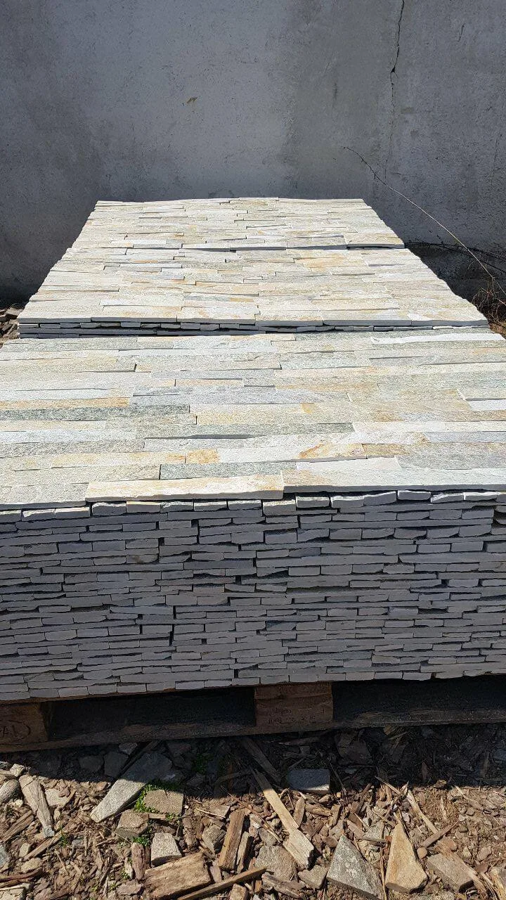 Pallets of light cut gneiss strips stacked high at the stone yard.