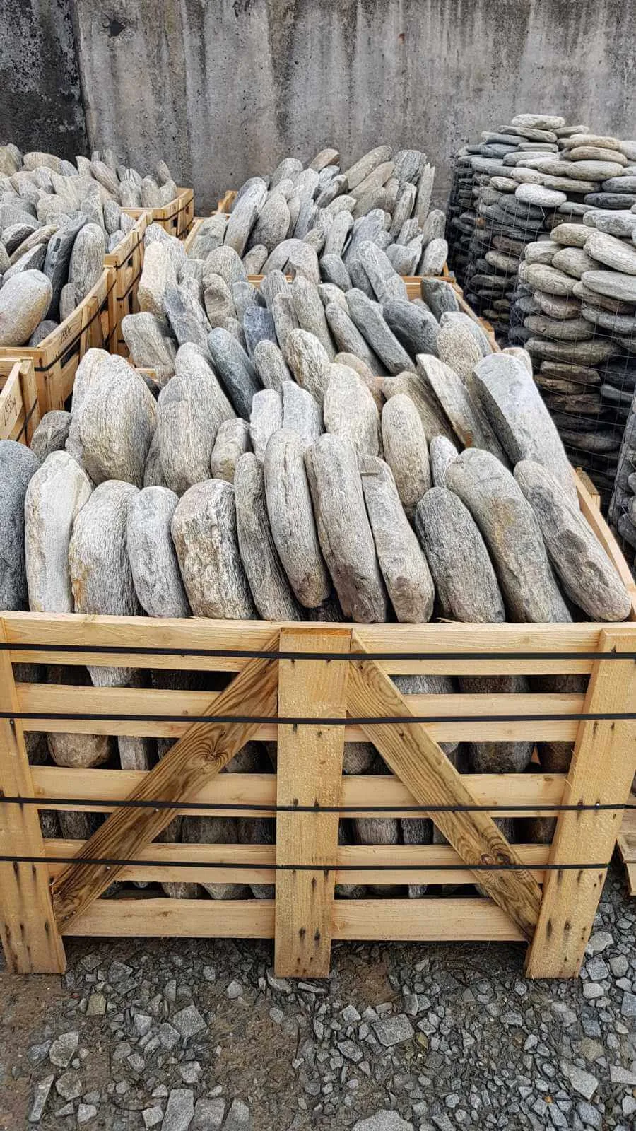 Wooden crates packed with elongated gneiss boulder stones at the stone yard