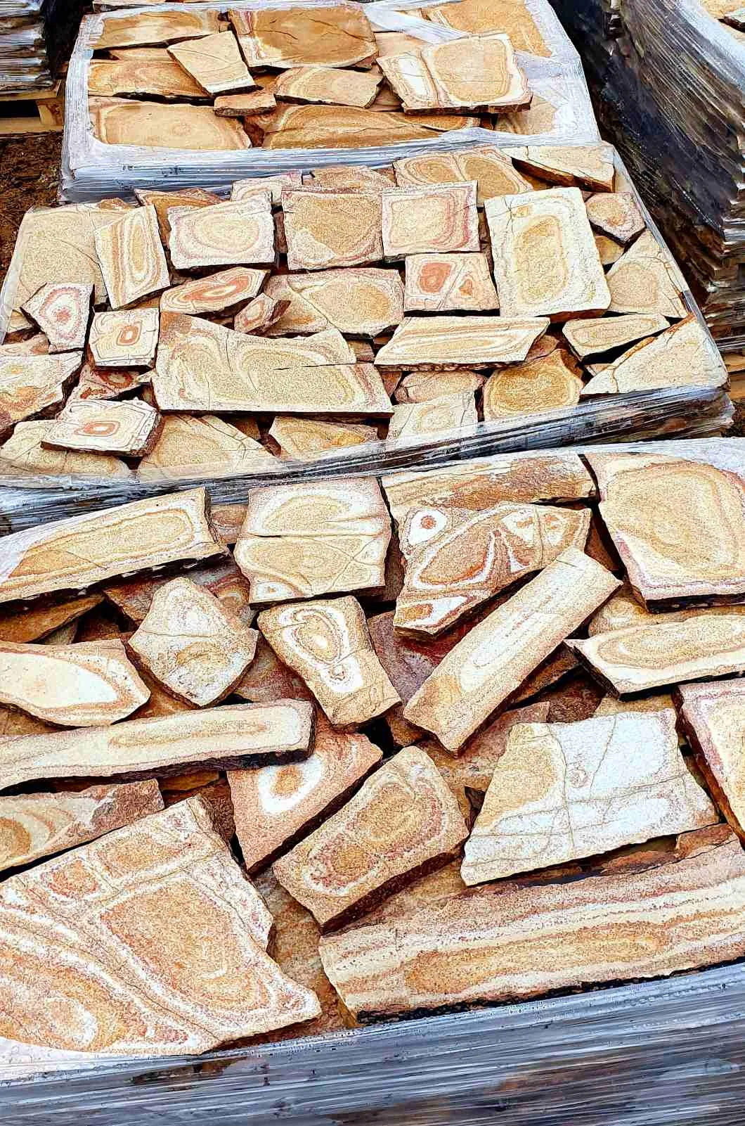 Pallets of irregular gneiss flagstones with swirling orange patterns
