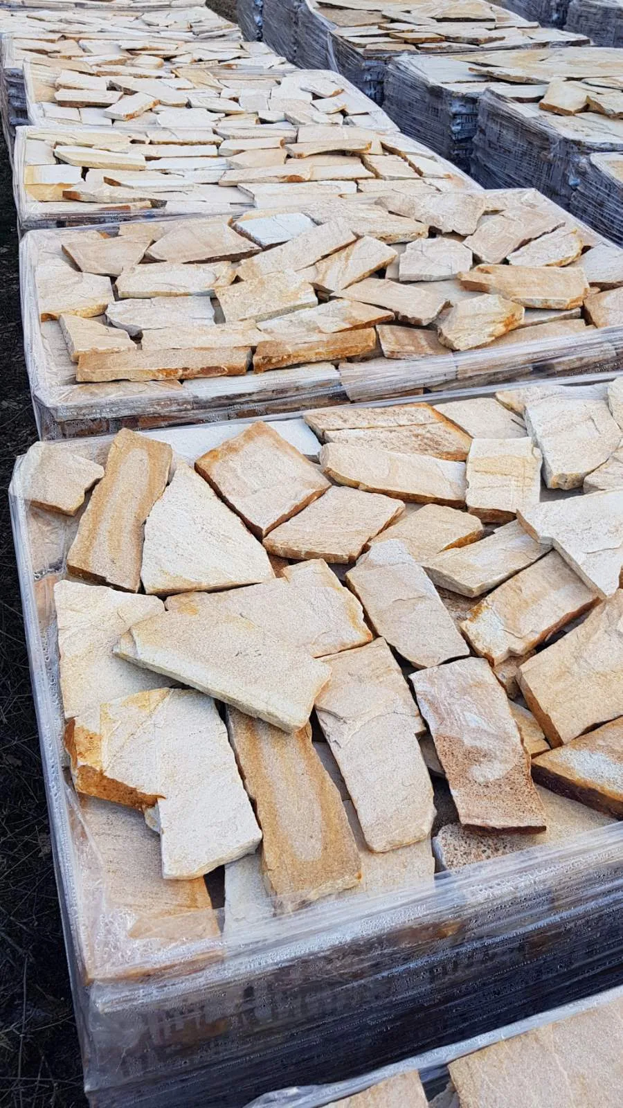 Rows of pallets with sand-colored irregular gneiss flagstones