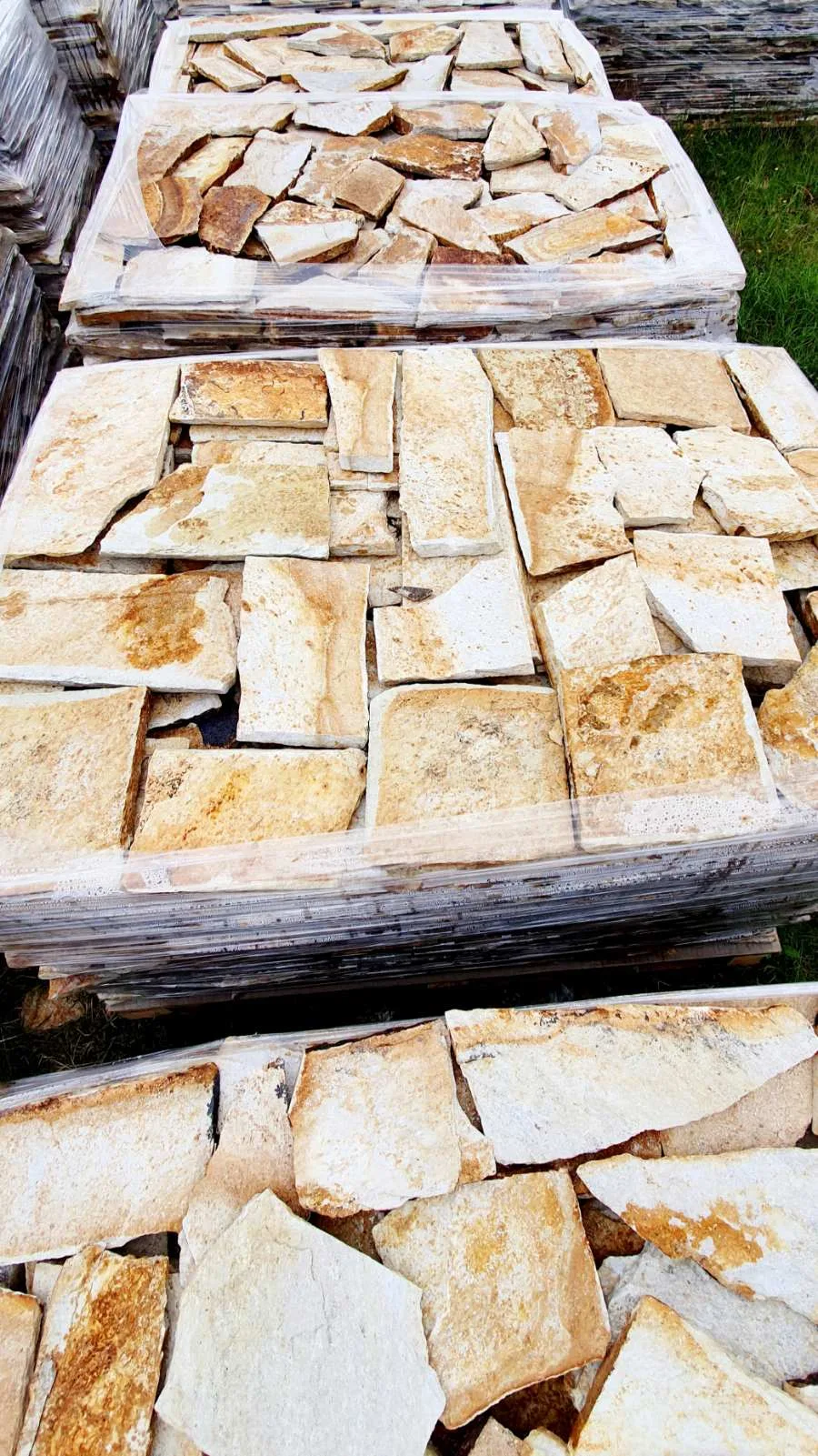 Pallets of cream and gold irregular gneiss flagstones at the yard