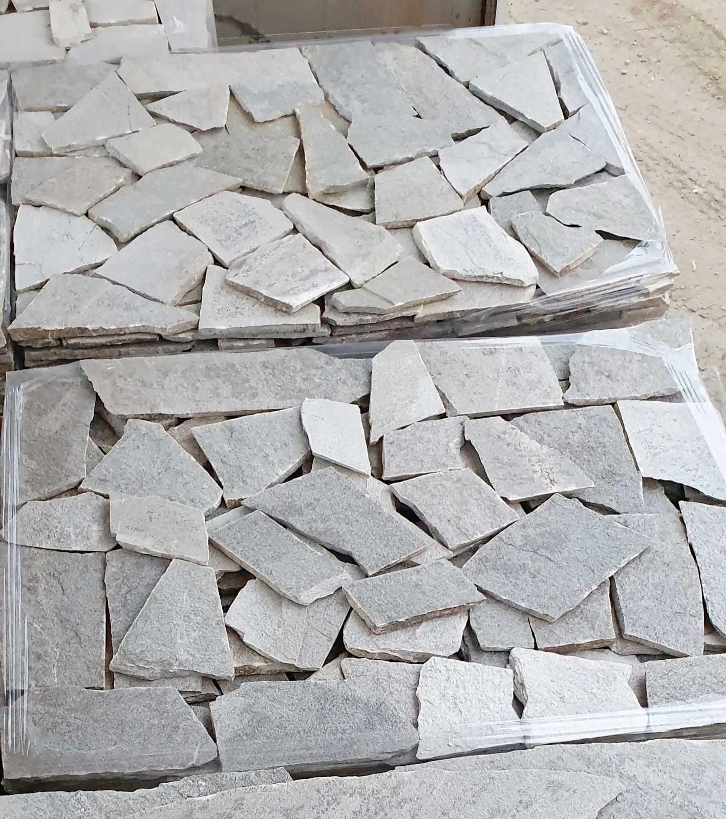 Wrapped pallets of light-gray irregular gneiss flagstones