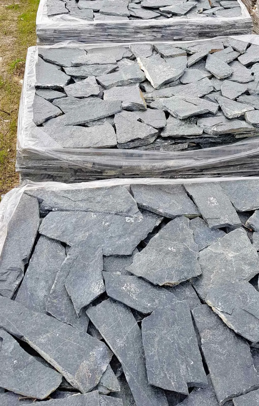 Wrapped pallets of dark gray irregular gneiss flagstones