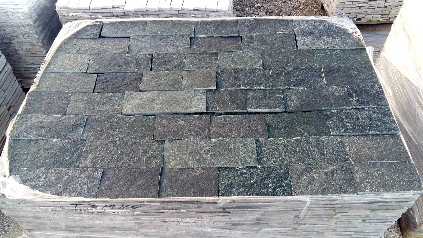 Pallet of dark precision-cut gneiss cladding tiles wrapped for shipping