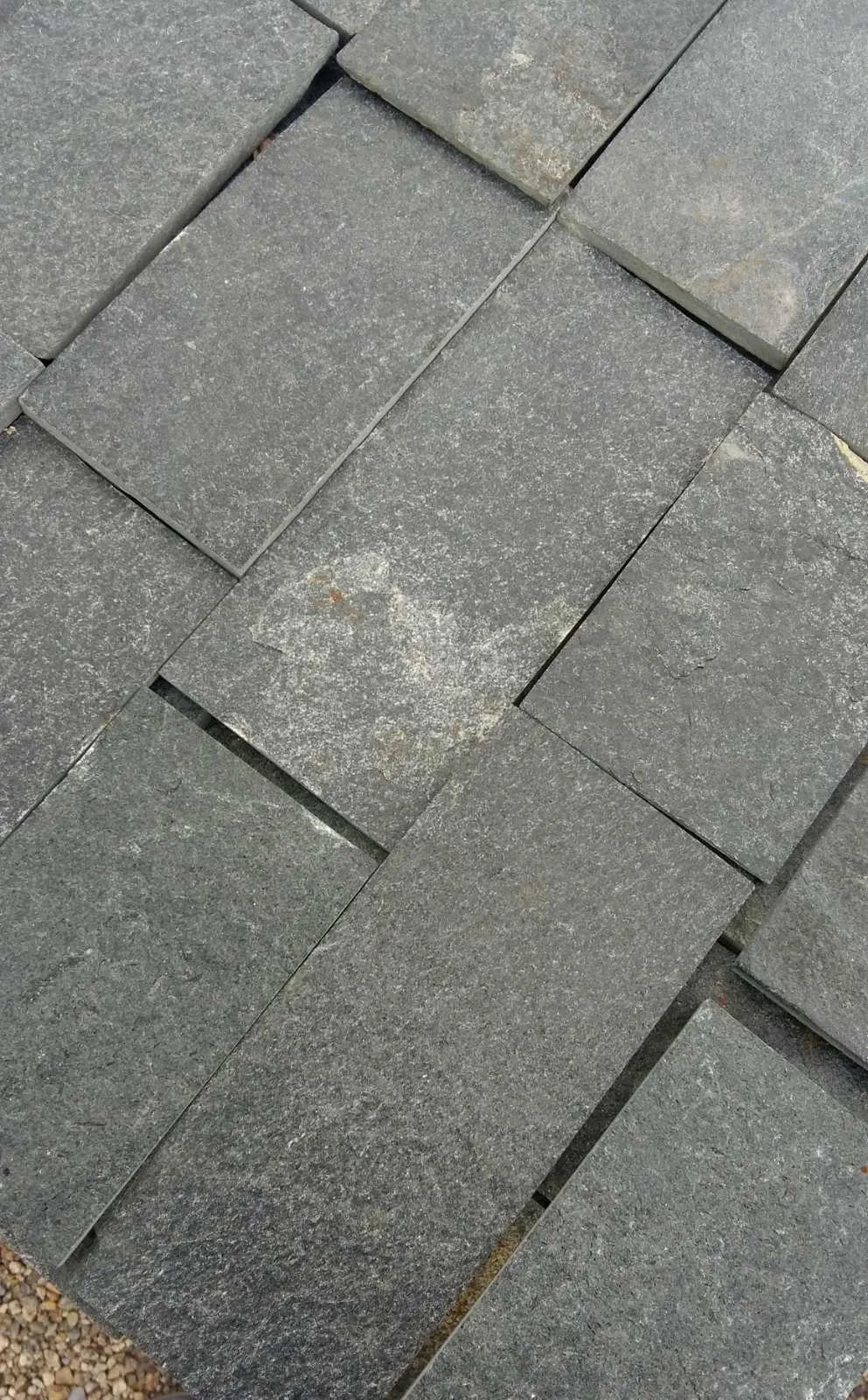 Close-up of gray precision-cut gneiss paving tiles on a pallet