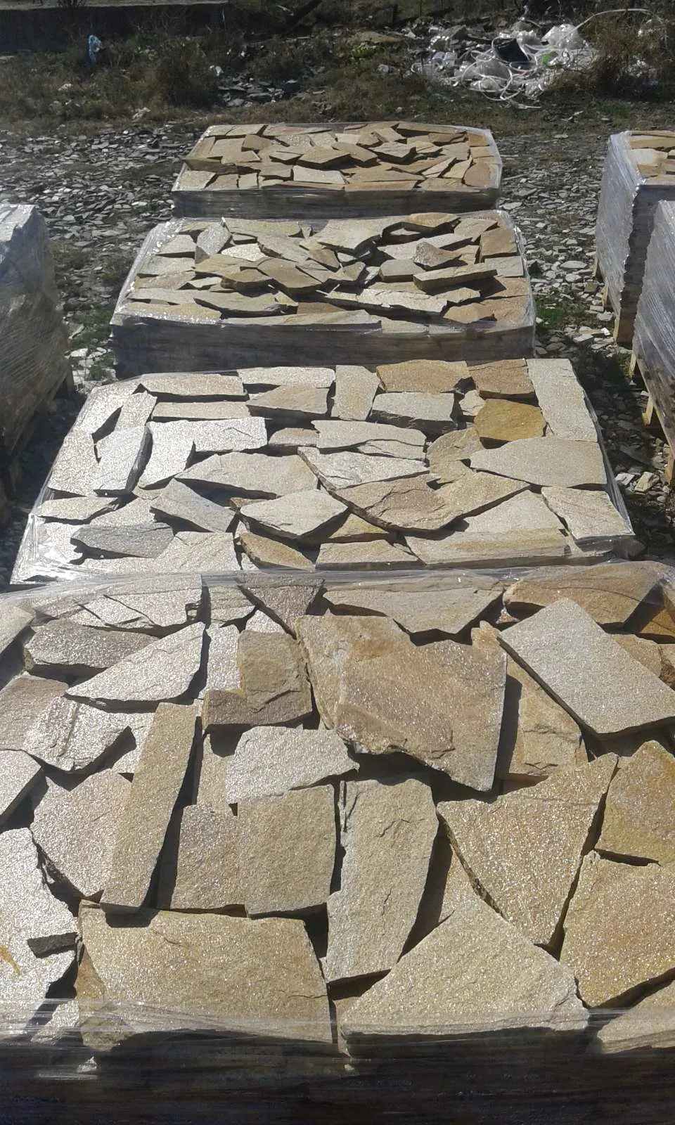 Pallets of yellow-beige irregular gneiss flagstones at the stone yard
