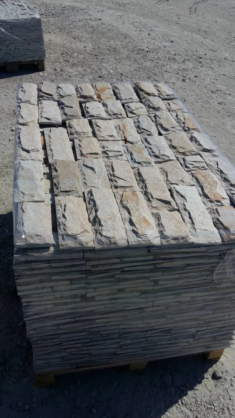 Pallet of split-face cut gneiss cladding stones stacked for shipping