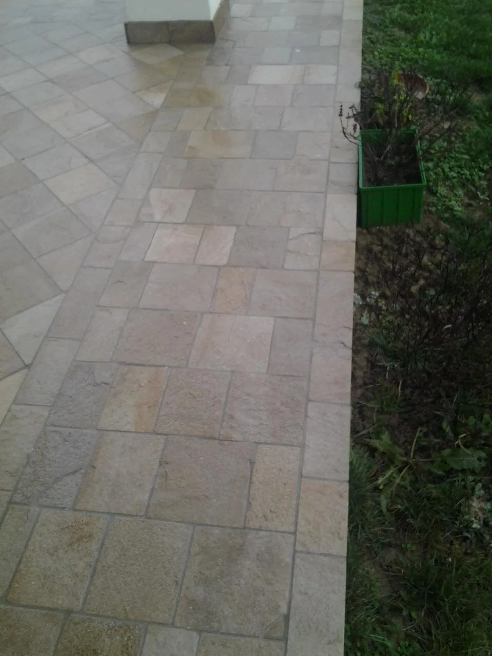 House terrace paved with precision-cut gneiss tiles beside a lawn