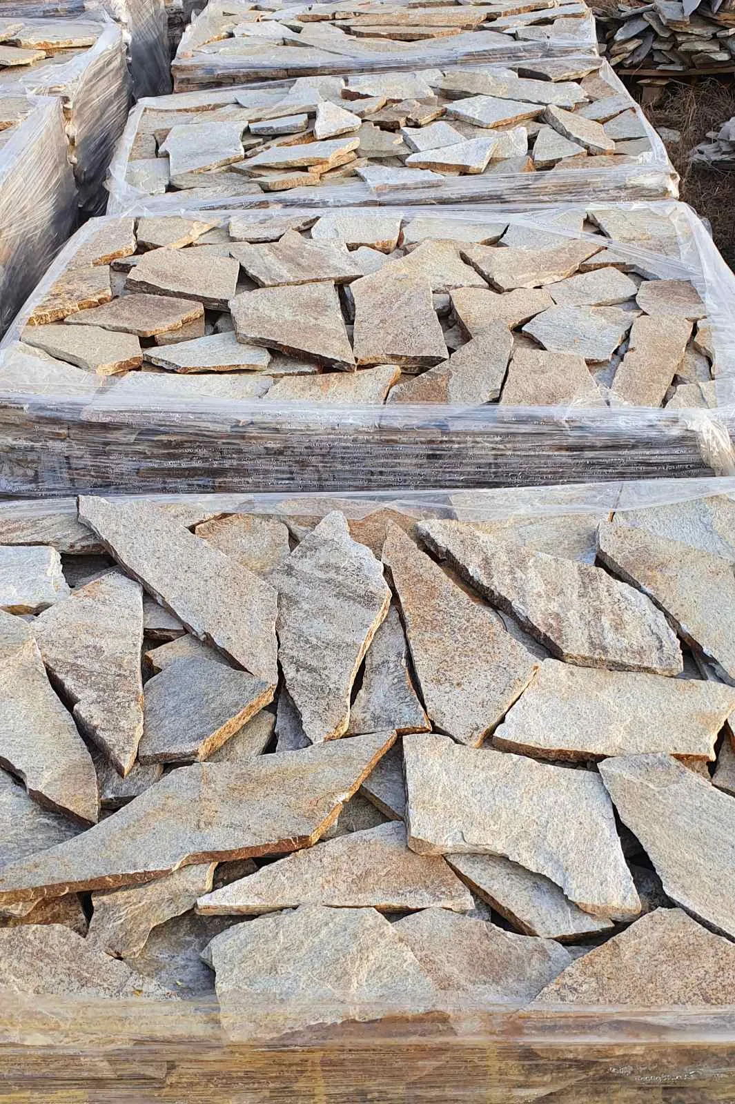 Pallets of irregular gneiss flagstones wrapped in foil at the stone yard