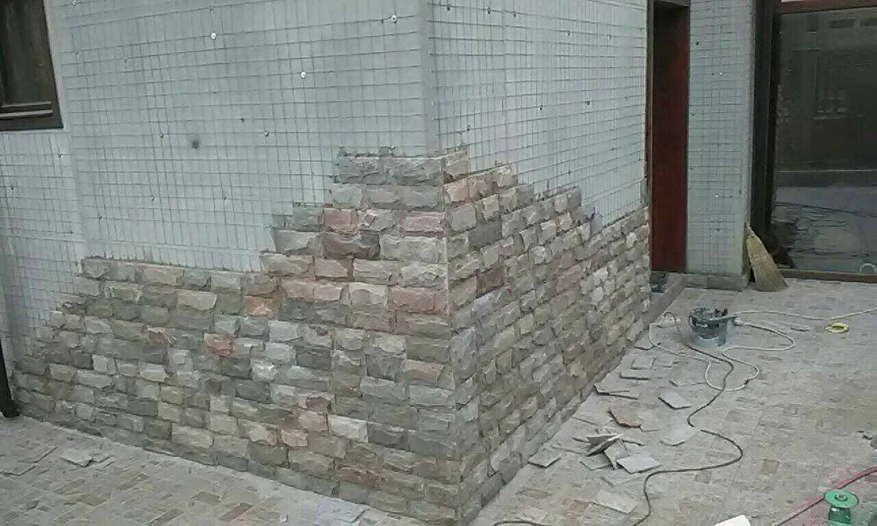 House corner being clad with rock-faced rectangular gneiss blocks