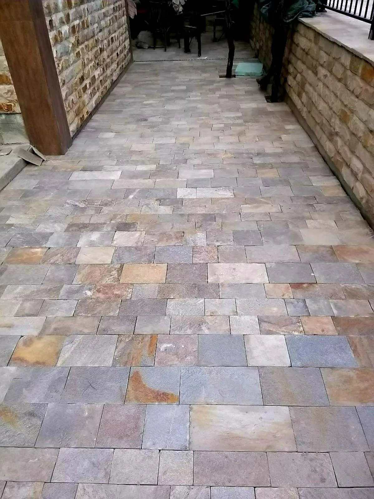 Finished terrace paved with multicolored cut gneiss tiles between stone walls
