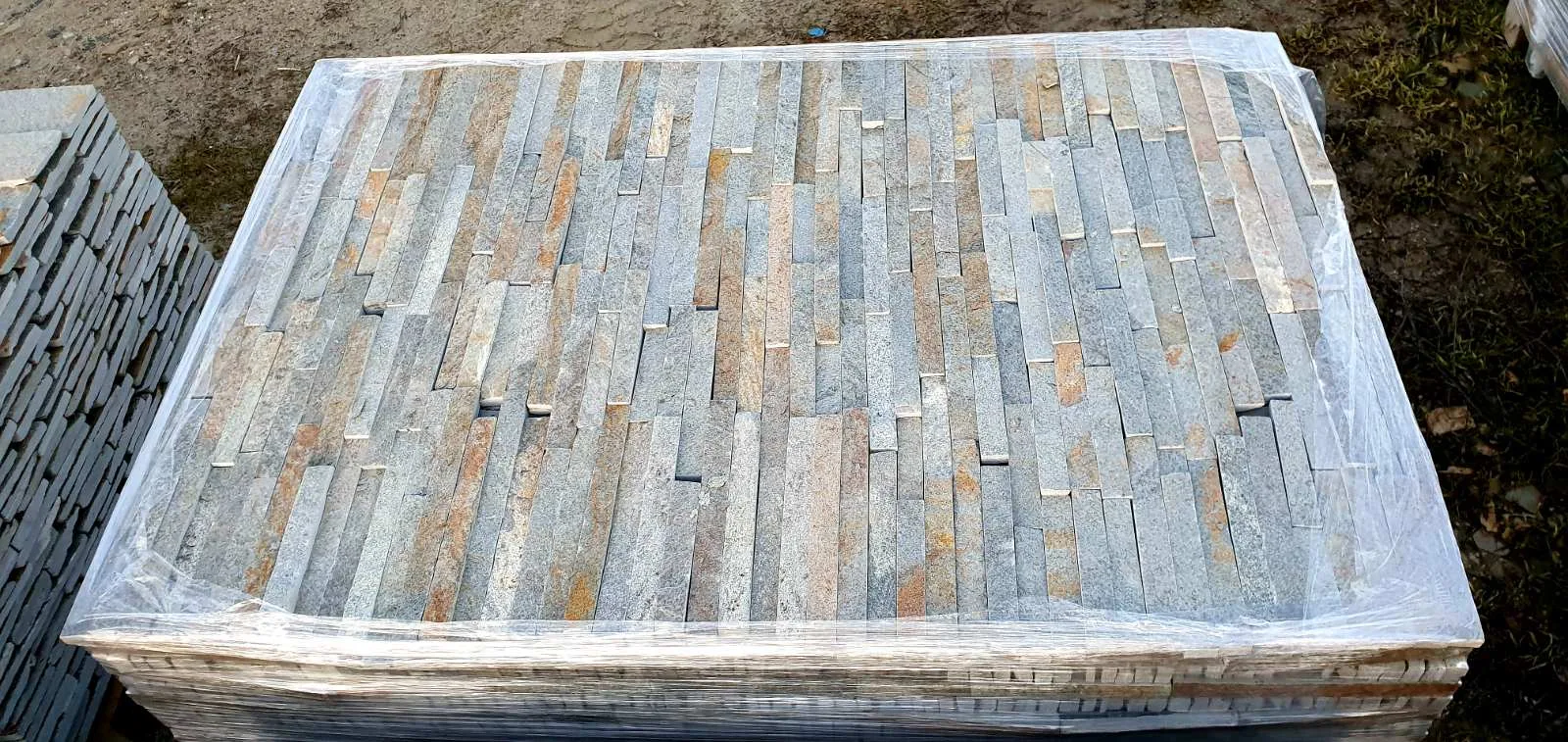 Foil-wrapped pallet of beige and gray cut gneiss cladding strips