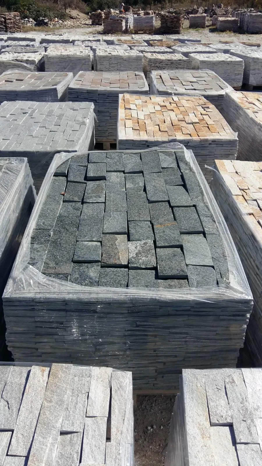 Pallets of green-gray cut gneiss tiles stacked in the stockyard