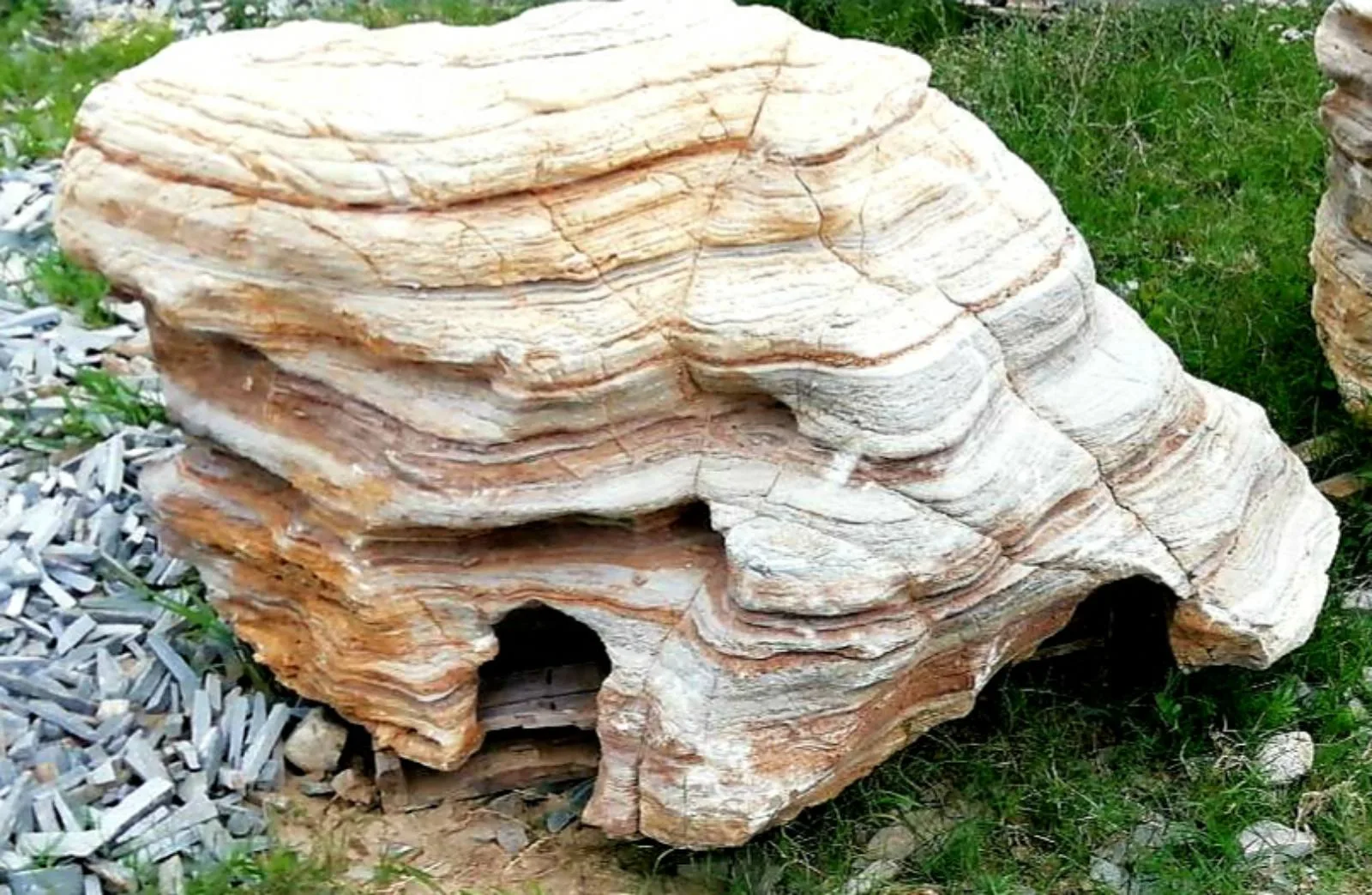 Large layered decorative boulder for garden rockeries displayed on grass
