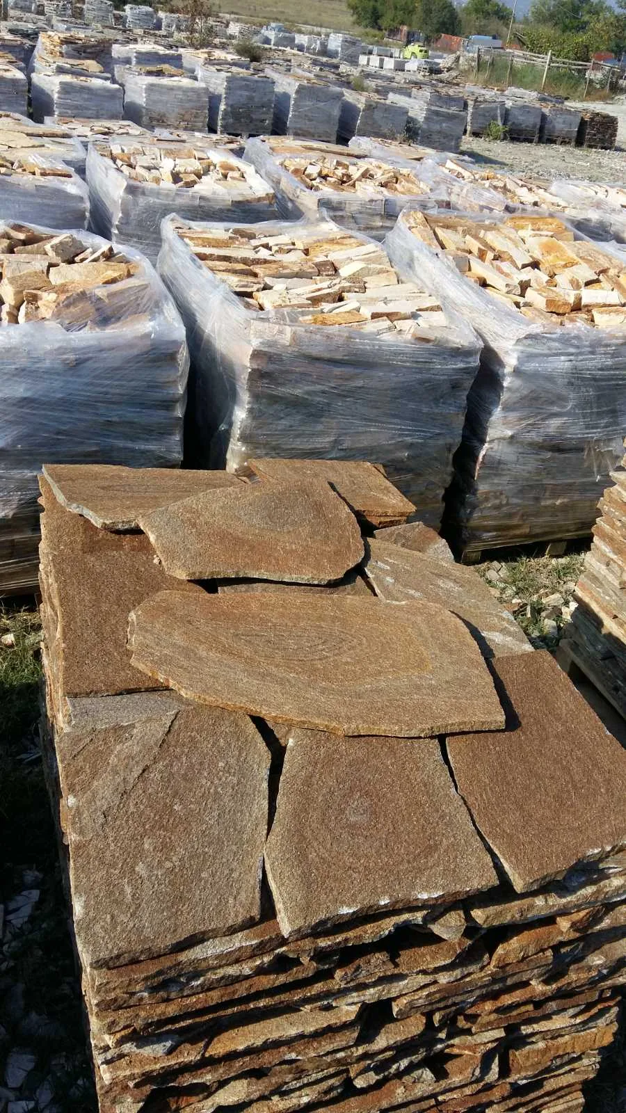 Stockyard with pallets of brown irregular gneiss flagstones