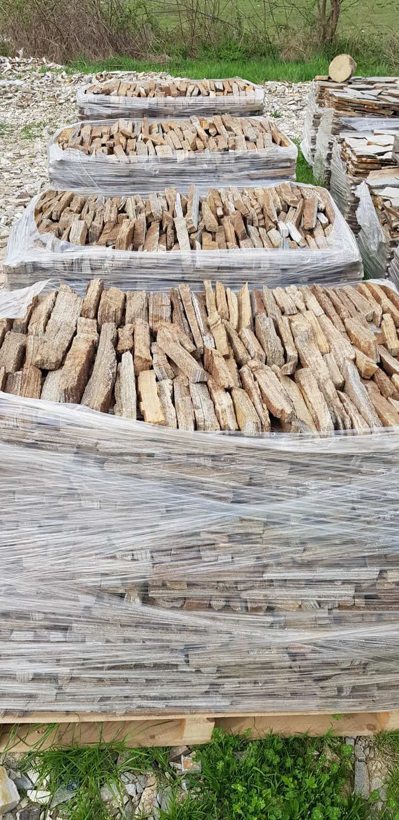 Pallets of narrow gneiss wall strips packed in foil at the stone yard