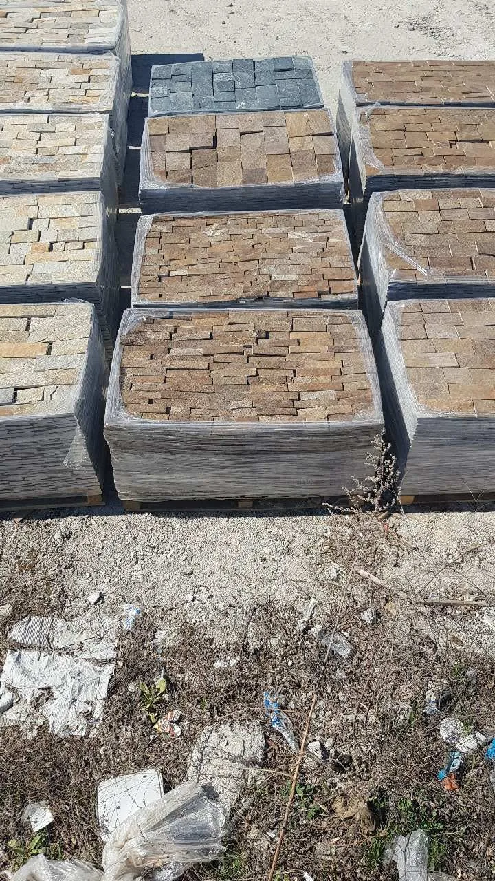 Pallets of cut gneiss cladding stones in brown and grey tones at the yard
