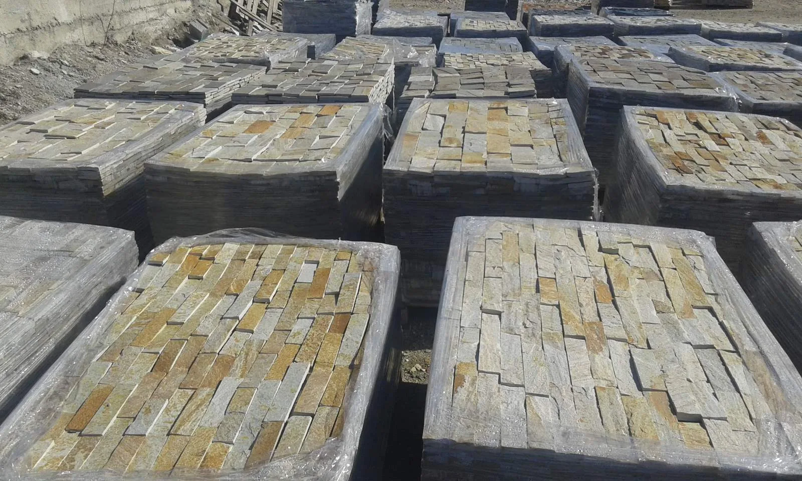 Rows of palletized cut gneiss strips stored at the production site