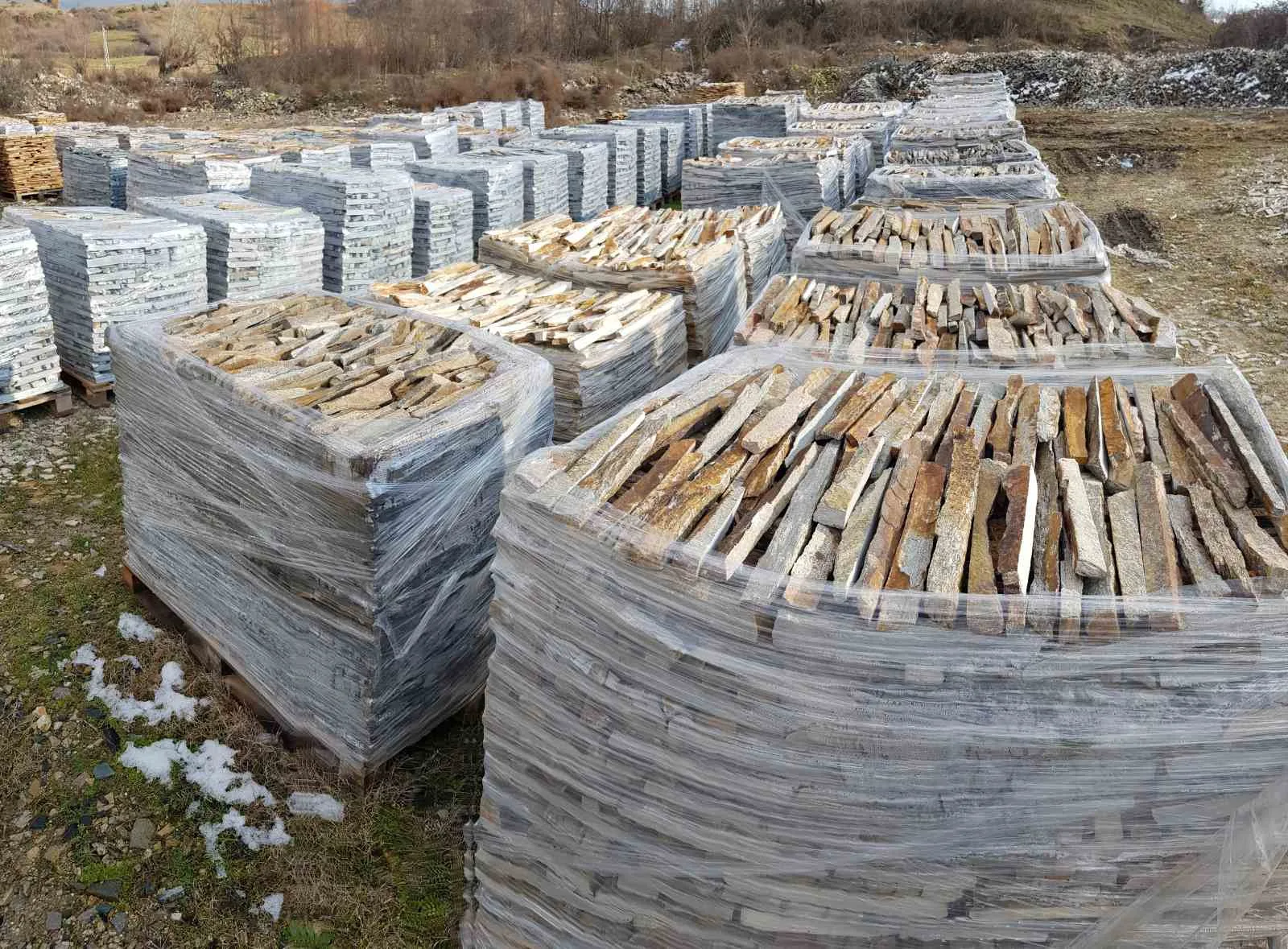 Stacked pallets of gneiss wall strips ready for shipment in the winter storage yard