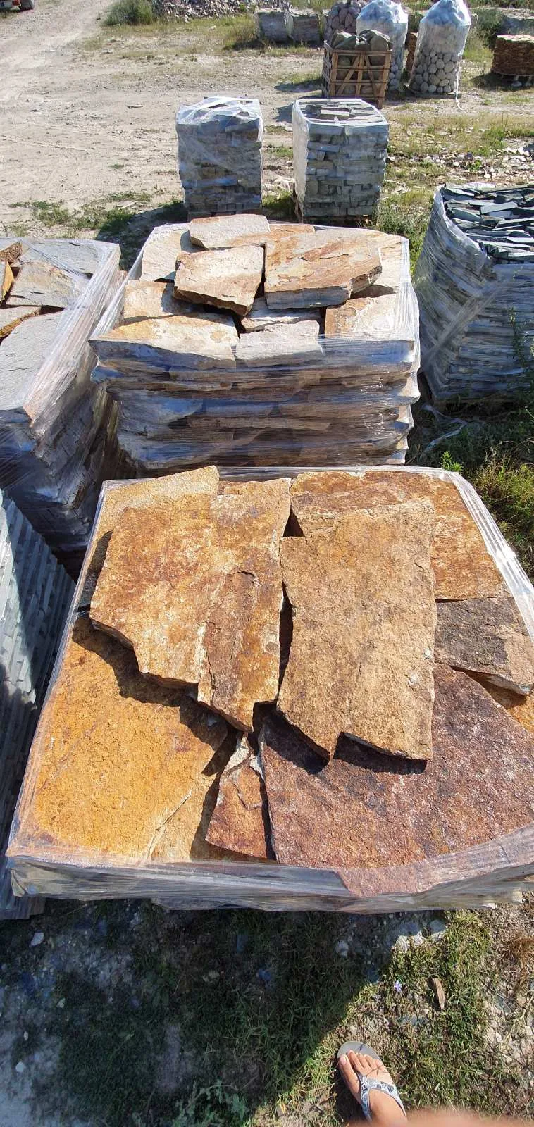 Pallets of irregular gneiss flagstones with bagged pebbles at the stone yard