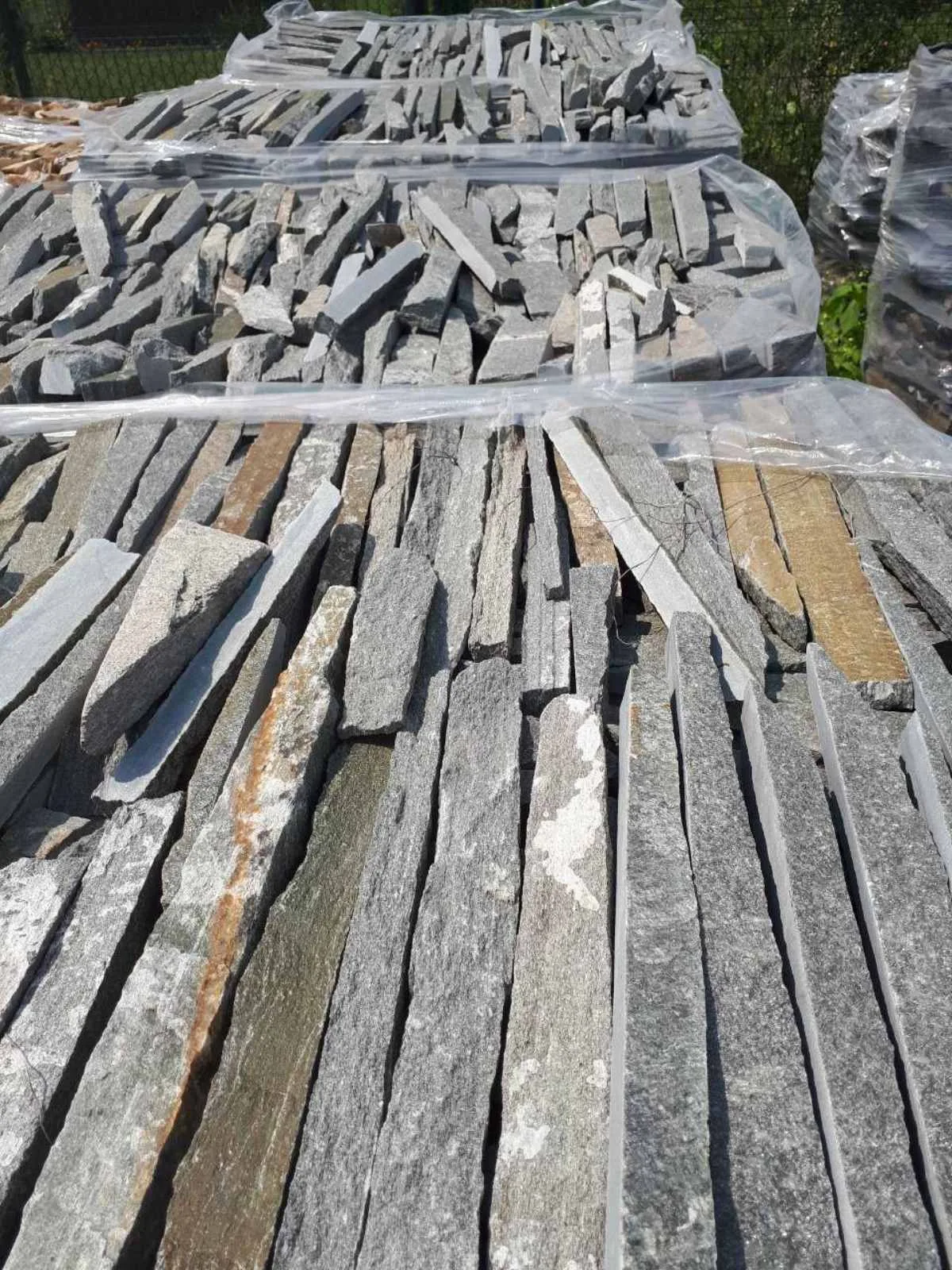 Pallets of thin grey gneiss strips packed in foil at the yard