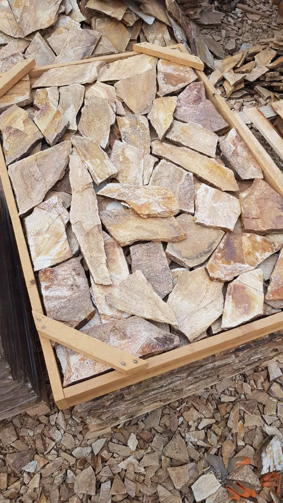 Wooden crate filled with irregular beige gneiss flagstones