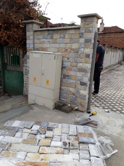 Street fence wall and gate pillars clad with squared gneiss blocks